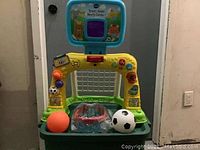 Full frontal view of the VTech Smart Shots Sports Center PlaySet with two balls placed in front, showing interactive panel and plastic base.