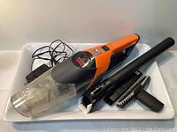 Overall view of cordless hand vacuum with attachments including charging cord and brushes