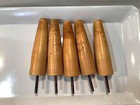 Front view of the five wooden tapered furniture legs showing wood grain and screw attachment.