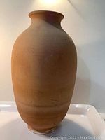 Full side view of the large terracotta vase showing smooth body and wide mouth.