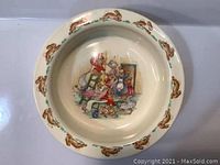 Top view of cream-colored ceramic baby bowl with decorative bunny illustrations around rim and central Bunnykins character scene inside bowl.
