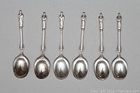 Top-side view of 6 English Apostle demitasse spoons lined up showing apostle figure handles and bowl shape