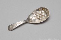 Clear close-up of the sterling silver spoon showing detailed etched floral design and hallmarks.