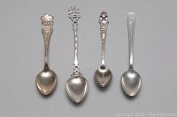 All four demitasse spoons arranged in single row handle up showing design details and overall condition