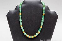 Front view of 16-inch jadeite bead necklace with gold-colored spacers on black bust display.