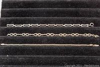 Three sterling silver bracelets laid out side-by-side on black velvet background showing chain styles and clasps