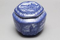 Front angle view of the hexagonal blue and white tea caddy showing detailed castle and architectural scene on the lid and body.