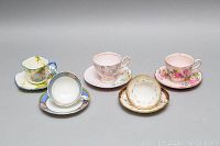 Full display of six assorted vintage teacups and saucers from Aynsley, Hammersley, Colclough, Tuscan, and Court with varied floral and scenic decor.