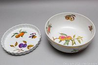 Top and side views of large serving bowl and pie plate showing fruit designs and gold trim