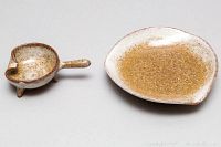 Two mid century pottery ashtrays, showing side and top views. One with handle and three legs, other rounded triangular shape.