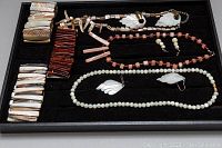 Full view of costume jewelry set arranged in a black tray showing necklaces, bracelets, and earrings of mother of pearl beads and leaf-shaped designs.