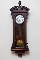 Front view of clock showing full wood case, dial, pendulum