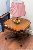 Photo of wooden accent table with brass lamp on top, showing table surface and lamp shade.