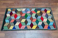 Full view of the colorful geometric hooked rug laid flat on wooden floor