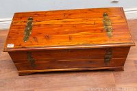 Closed view of the wooden cedar chest showing brass hinges and finish condition.