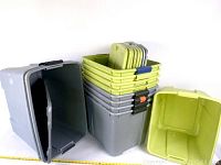 Multiple bins stacked in two stacks showing green lids and grey bins, along with lids stacked separately.