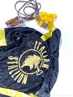 Boxing robe spread out showing full back graphic and color scheme alongside yellow hand wraps and jump rope coiled.