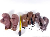 Pair of three different colored leather boxing gloves arranged with measuring tape showing size around 11 inches tall