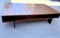 Full angled view of coffee table showing veneer surface and open shelf beneath, metal legs partially visible.