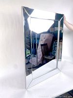 Front view of rectangular wall mirror showing beveled glass center and reflective frame, held upright for display.
