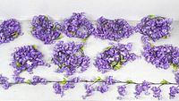 Ten strands of six-foot long purple artificial silk wisteria vines laid out flat showing flower clusters and leaves along brown vine stems.
