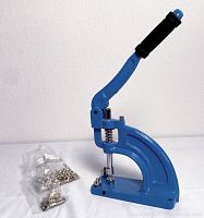 Front angle photo showing blue hand press, foam handle, base, and bag of metal grommets beside it.