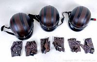 Top view of three half helmets with brown textured leather-style surface and black stripes, along with three pairs of brown fingerless gloves lined up beneath.