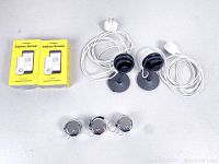 Overview of all items: two Nest cameras on stands with cables and adapters, two boxed Kangaroo motion sensors, three silver KTRIO tally counters.