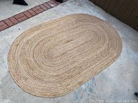 Top view of oval natural jute rug on concrete floor.