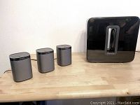 Three Sonos One speakers and one Sonos Sub Gen 3 subwoofer displayed on a table.