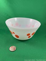 Angled side view showing orange polka dot pattern and size comparison with quarter coin.