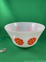 Front side view showing orange daisy flower pattern on white milk glass bowl with 7 inch diameter reference by a quarter coin