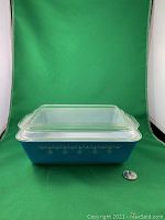 Blue glass rectangular dish with snowflake garland pattern and clear glass lid, shown with coin for scale.