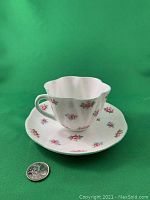 Shelley China cup with rosebud pattern and scalloped rim on matching saucer, coin for scale