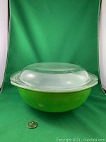 Pyrex Kelly Green casserole dish with clear glass lid on top, shown with a quarter for size reference
