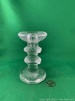 Front view of the Iittala Festivo 2 Ring textured glass candlestick beside a quarter for size reference, showing its two ring design and textured clear glass material.