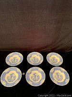 Six Royal Doulton blue and white transferware bowls arranged on a black cloth, showing overall design and size comparison with a coin.