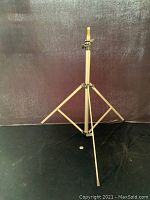 Front view showing the Manfrotto Art.060L light stand fully extended with three legs and yellow connector cap on top.