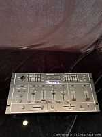 Front top view of Numark DM1200 DJ Mixer showing channel sliders, EQ sliders, knobs, and headphone jack.