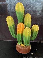 Front view of handcrafted wooden cactus with green and yellow painted arms and brown base.