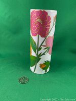 Front right side view of the cylindrical white vase with pink, orange, and green floral design alongside a US quarter for scale.