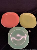 Three different colored oval Mid-Century Modern platters shown flat on black background.