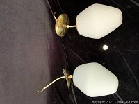 Pair of ceiling light fixtures lying flat showing the brass mounting plates and white frosted glass shades.