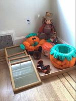Photo showing assorted Halloween decorations including scarecrows, pumpkin baskets, a Halloween bucket, Mickey mouse decorative shoes, and 8x10 photo frames stacked on the floor.