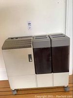 Front view of Bionaire humidifier with air vents, control panel, and two water tanks side-by-side on casters.