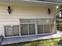 All six wood framed vintage single pane windows leaning against a wall outdoors, showing size variation and frame condition
