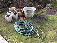 Full view of garden pots, hose coiled on ground, and wire fencing rolls