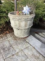 GardenStone large cement planter shown on stone steps with surrounding greenery.