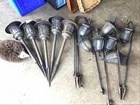 Overview of five stake lights, seven hanging lantern lights, and hedgehog boot brush on concrete floor.