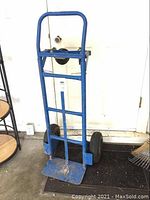 Full view of the blue steel hand truck showing frame, bottom loading plate, and large pneumatic wheels